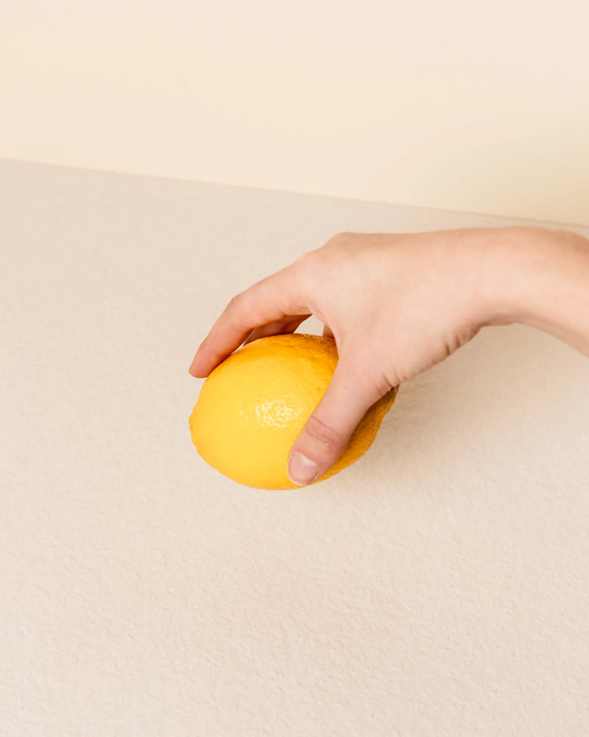 Hand, das eine Zitrone über dem cremebeigen Tablett des Classic PILOTIS Moduls hält, Nahaufnahme