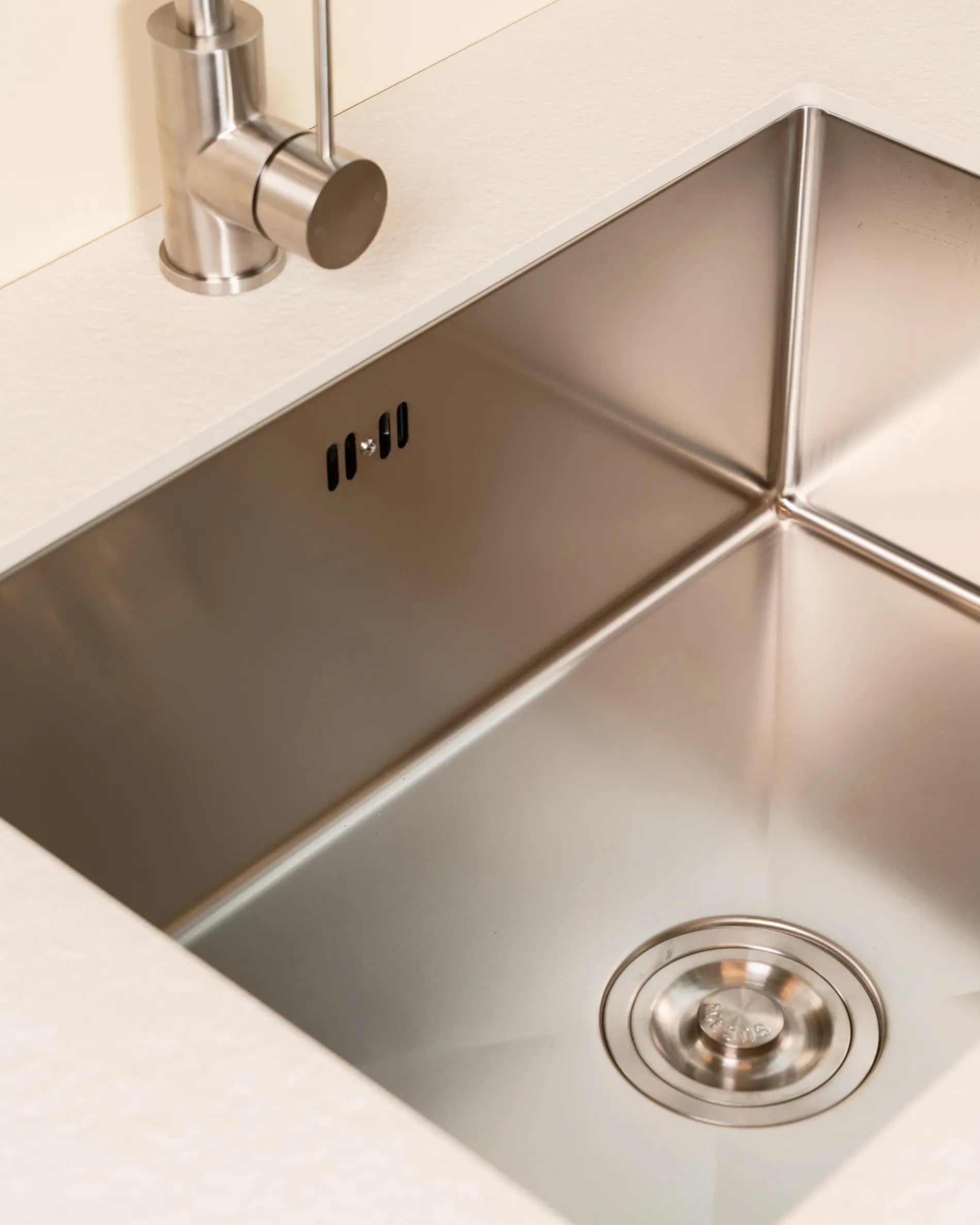 Edelstahlspüle des PILOTIS Spülmoduls, eingelassen in eine creme-beige Arbeitsplatte, Nahaufnahme