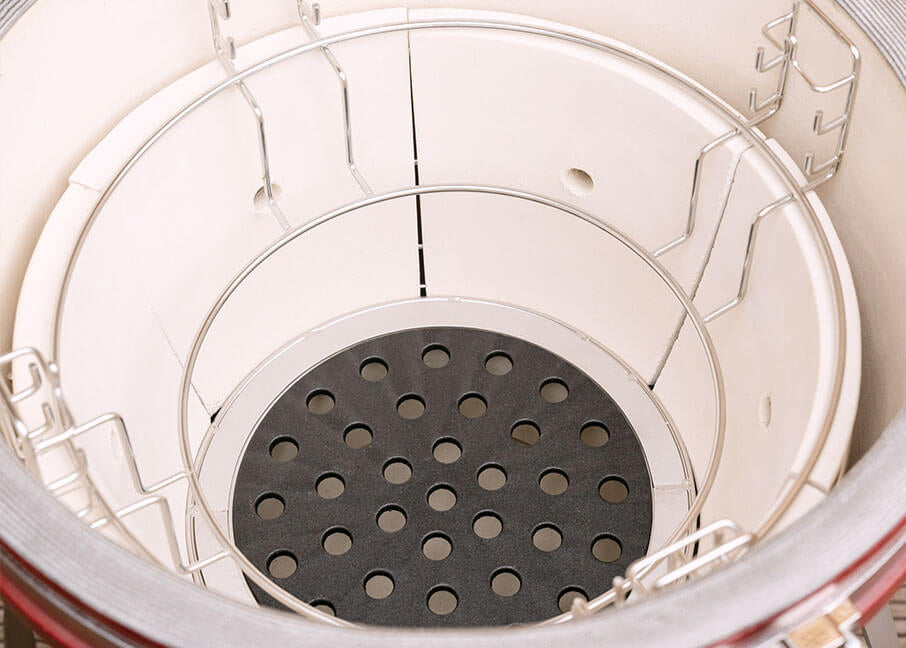 Vista interna della vasca in ceramica del kamado Kokko, con struttura divisa e fondo forato per la gestione della brace.