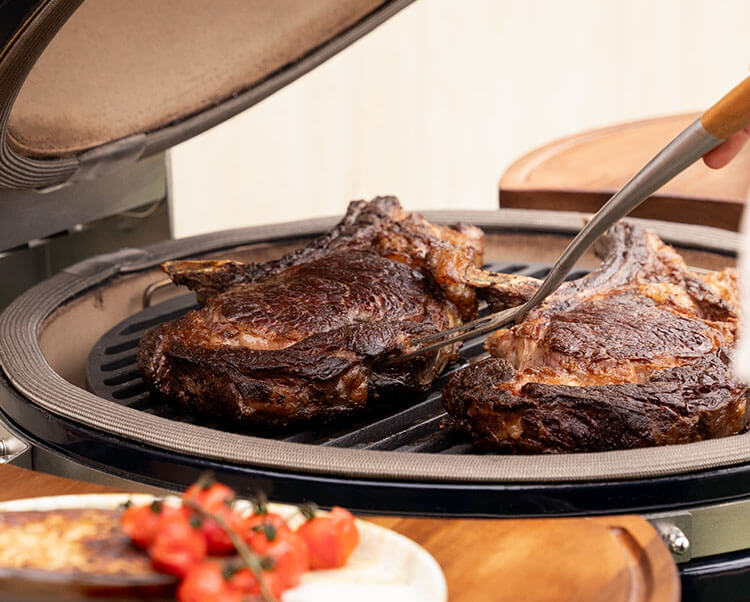 Cottura diretta su kamado Kokko XL 22 pollici, che mostra la rosolatura degli alimenti sulla griglia in acciaio inox.