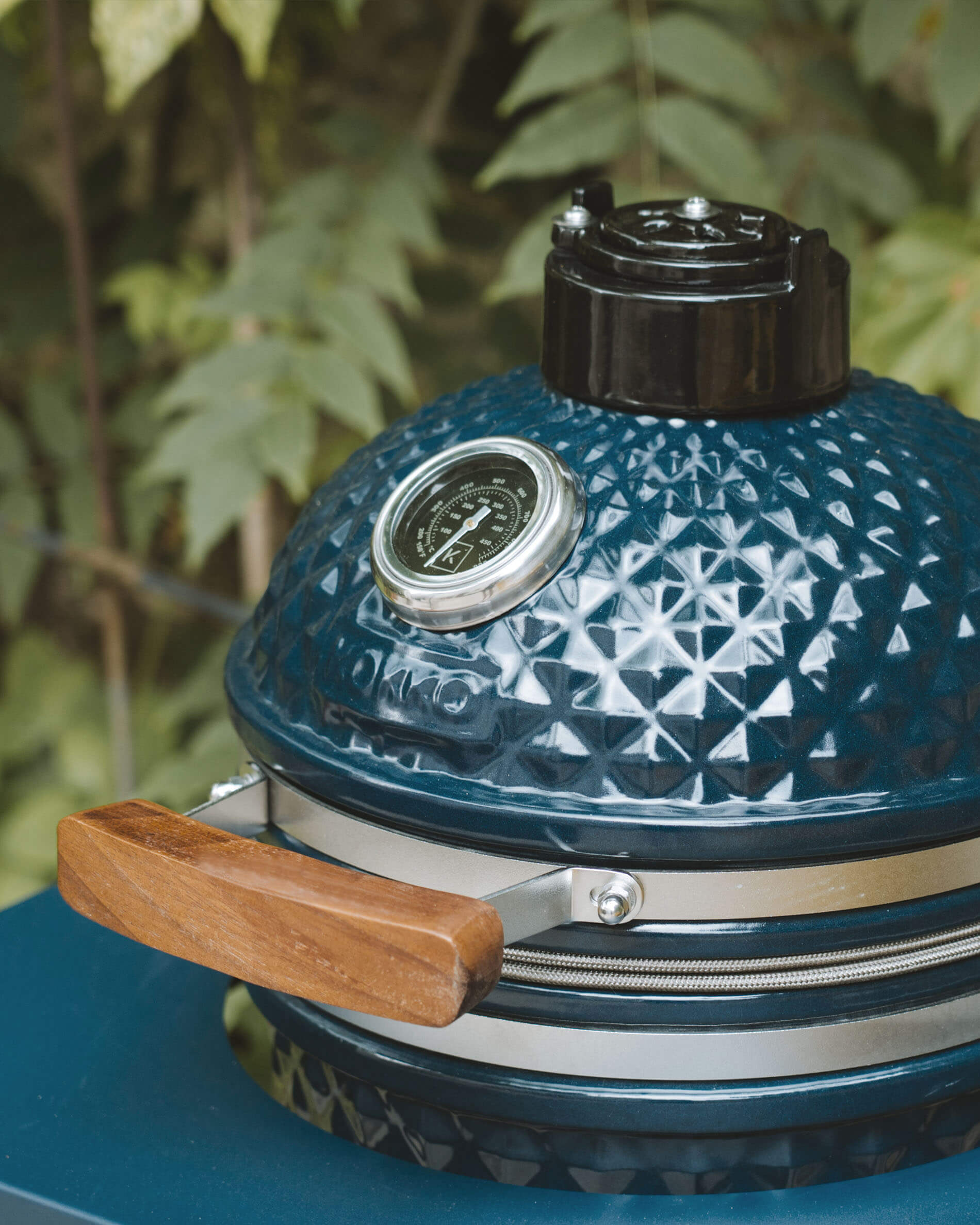 Detail des Deckels eines Kokko Kamado in Ozeanblau mit integriertem Thermometer und Holzgriff.