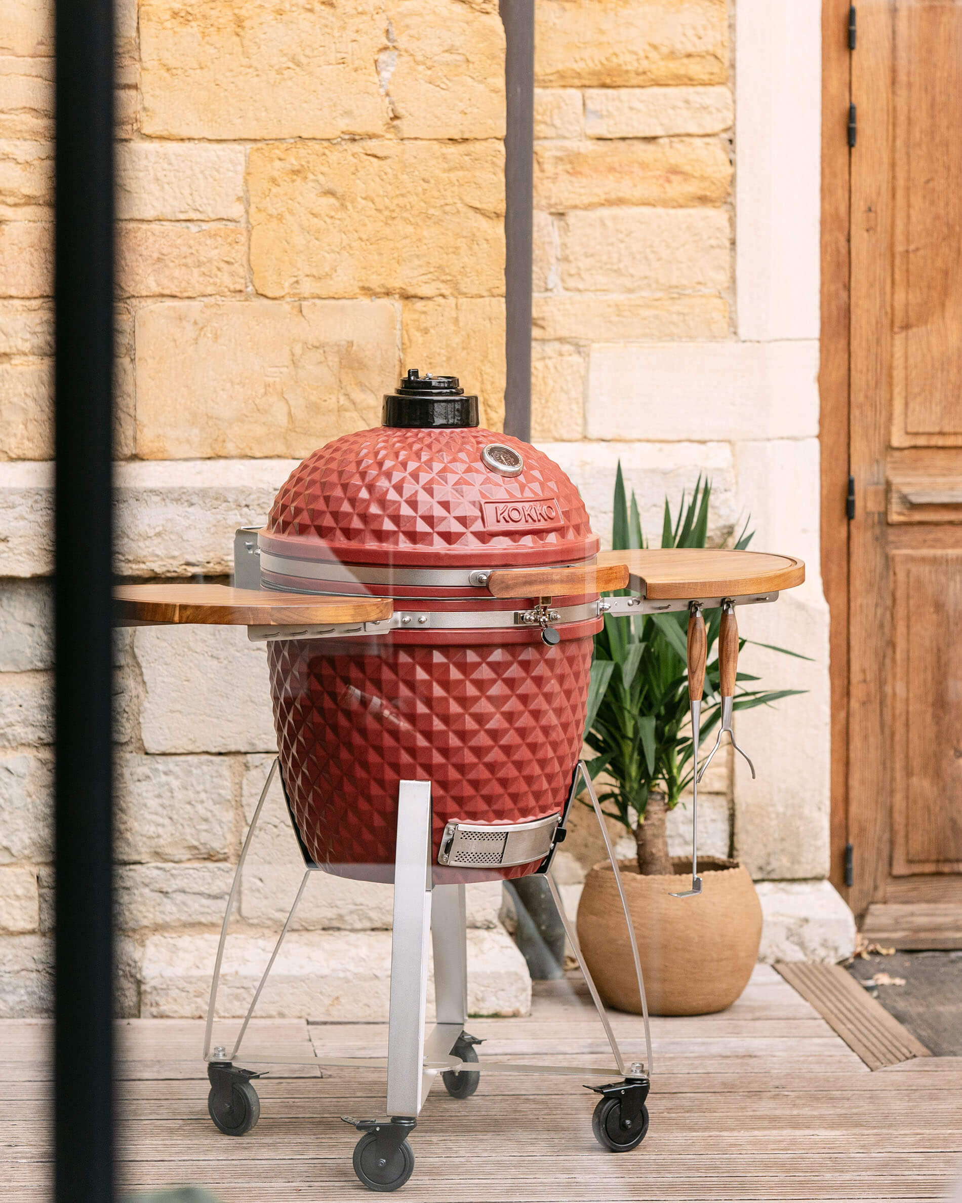 Kamado Kokko XL 22 pollici in ceramica rosso ossido installato su carrello all’esterno.