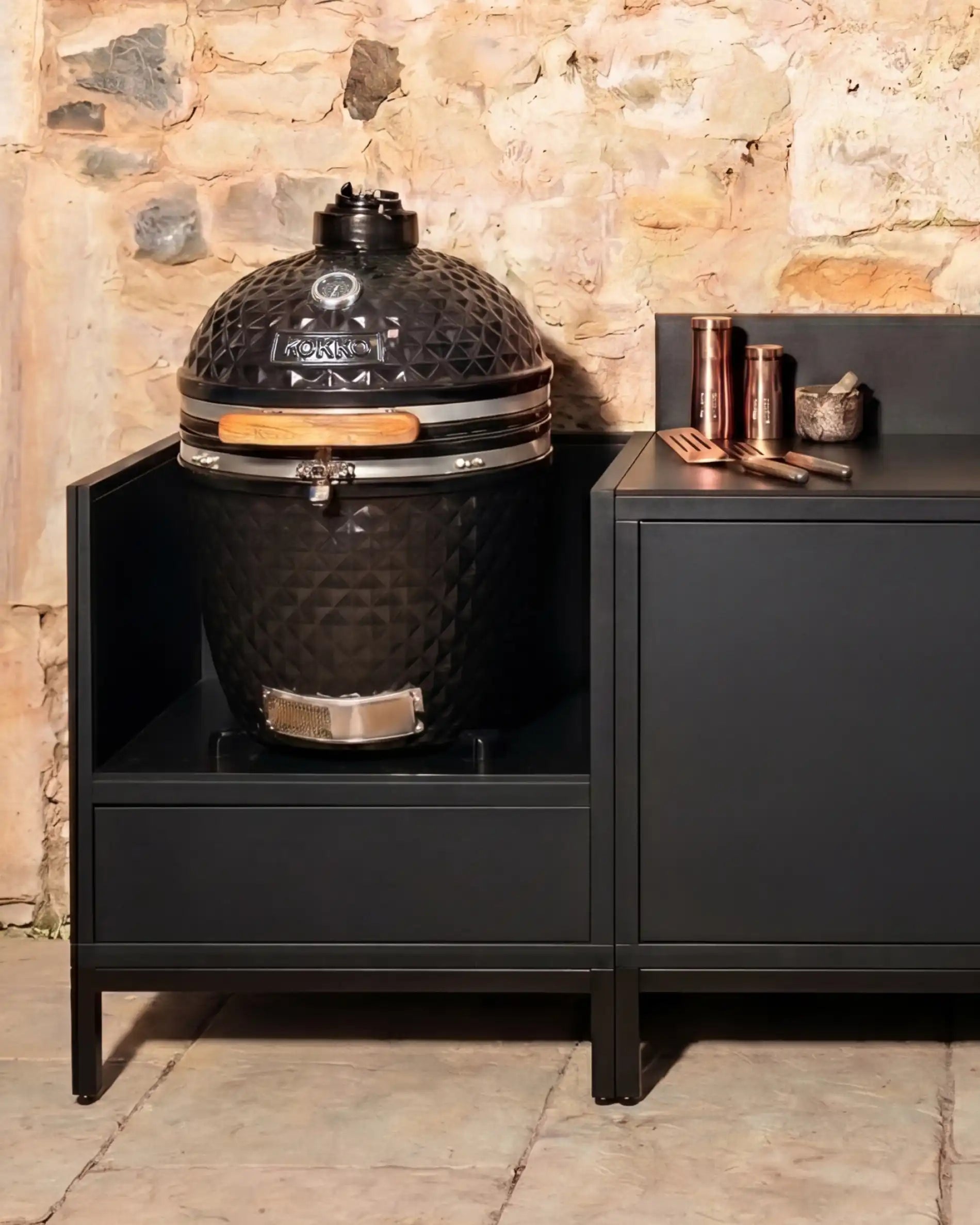 Kamado Kokko noir intégré dans cuisine extérieure avec rangements
