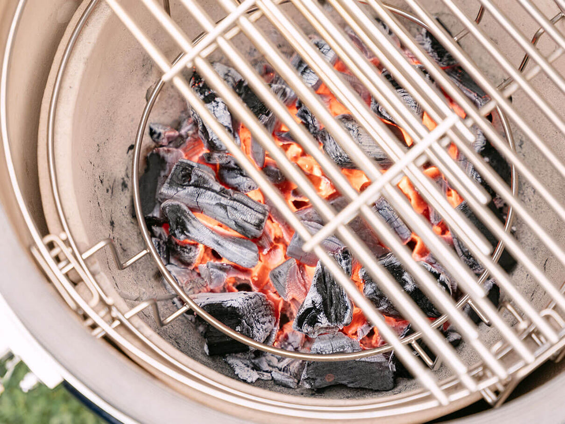 Charbon de bois incandescent dans la cuve en céramique d’un kamado Kokko, avec braises rouges visibles sous la grille inox, illustrant la montée en température et la maîtrise de la cuisson au feu de bois.