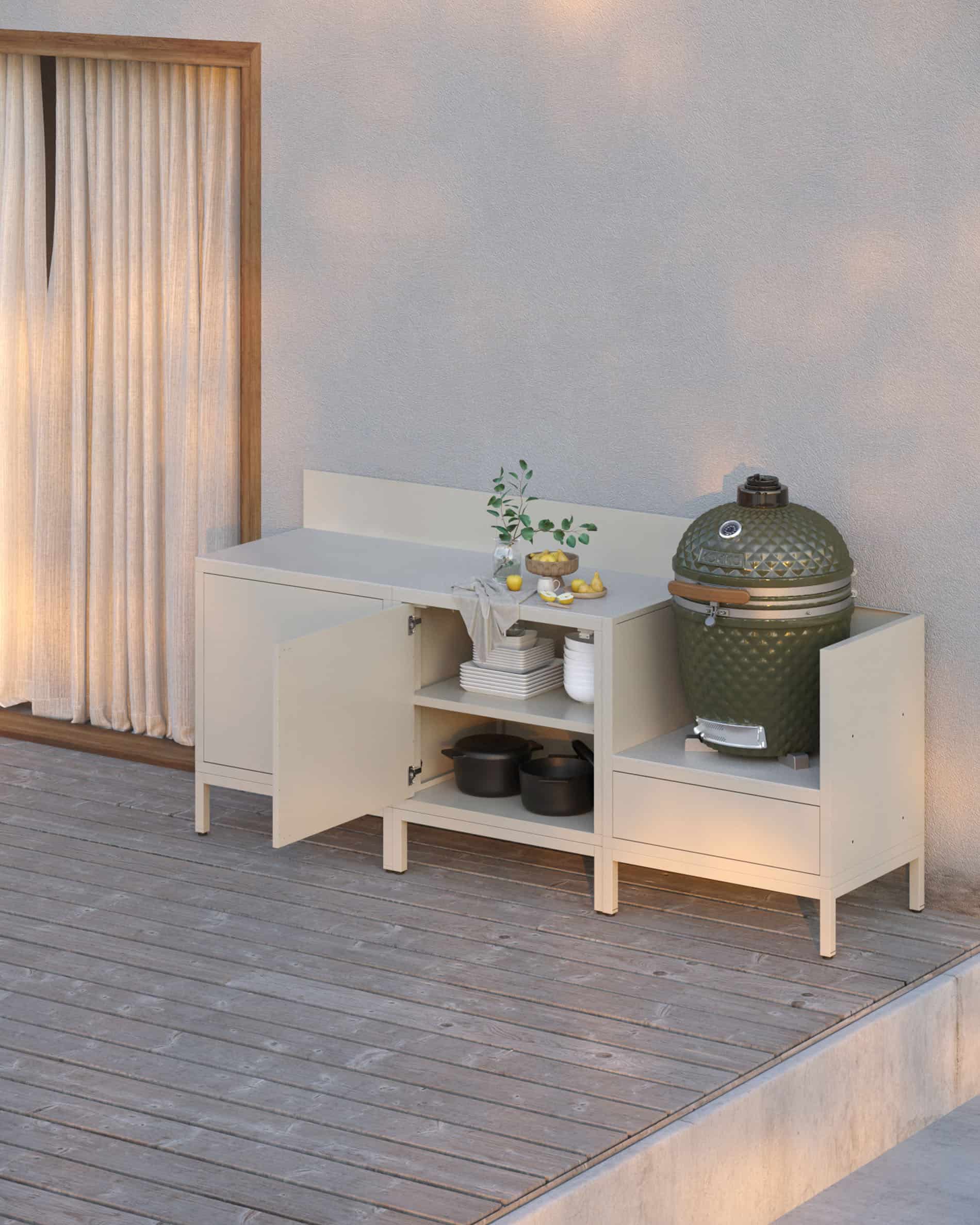 Cuisine pilotis coloris crème avec rangements ouverts et fermés, plan de travail clair, crédence assortie et module kamado intégré sur structure surélevée.