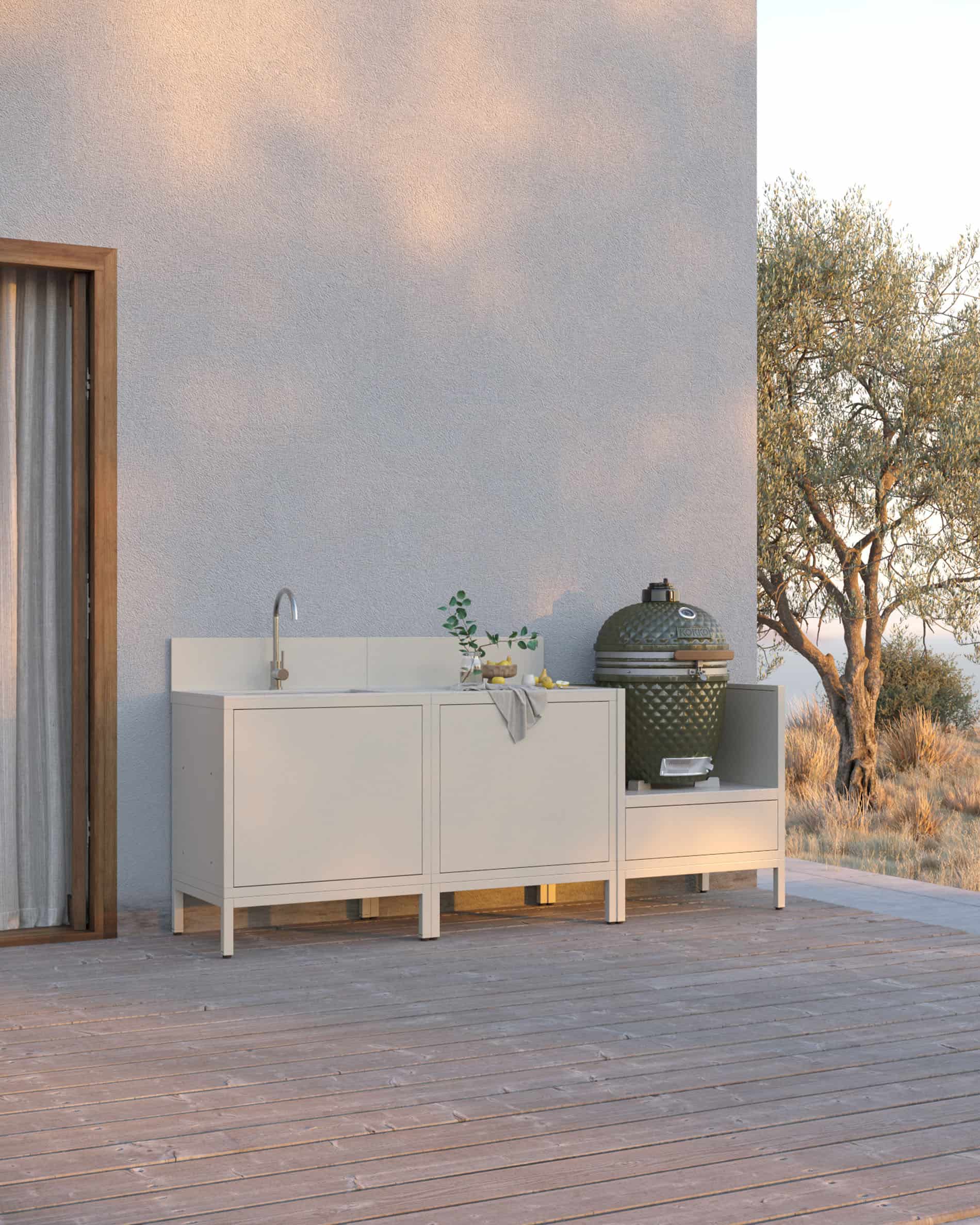 Cucina su palafitte color crema composta da tre moduli con lavello integrato, piano di lavoro chiaro e spazio dedicato al kamado, installata su una terrazza in legno.