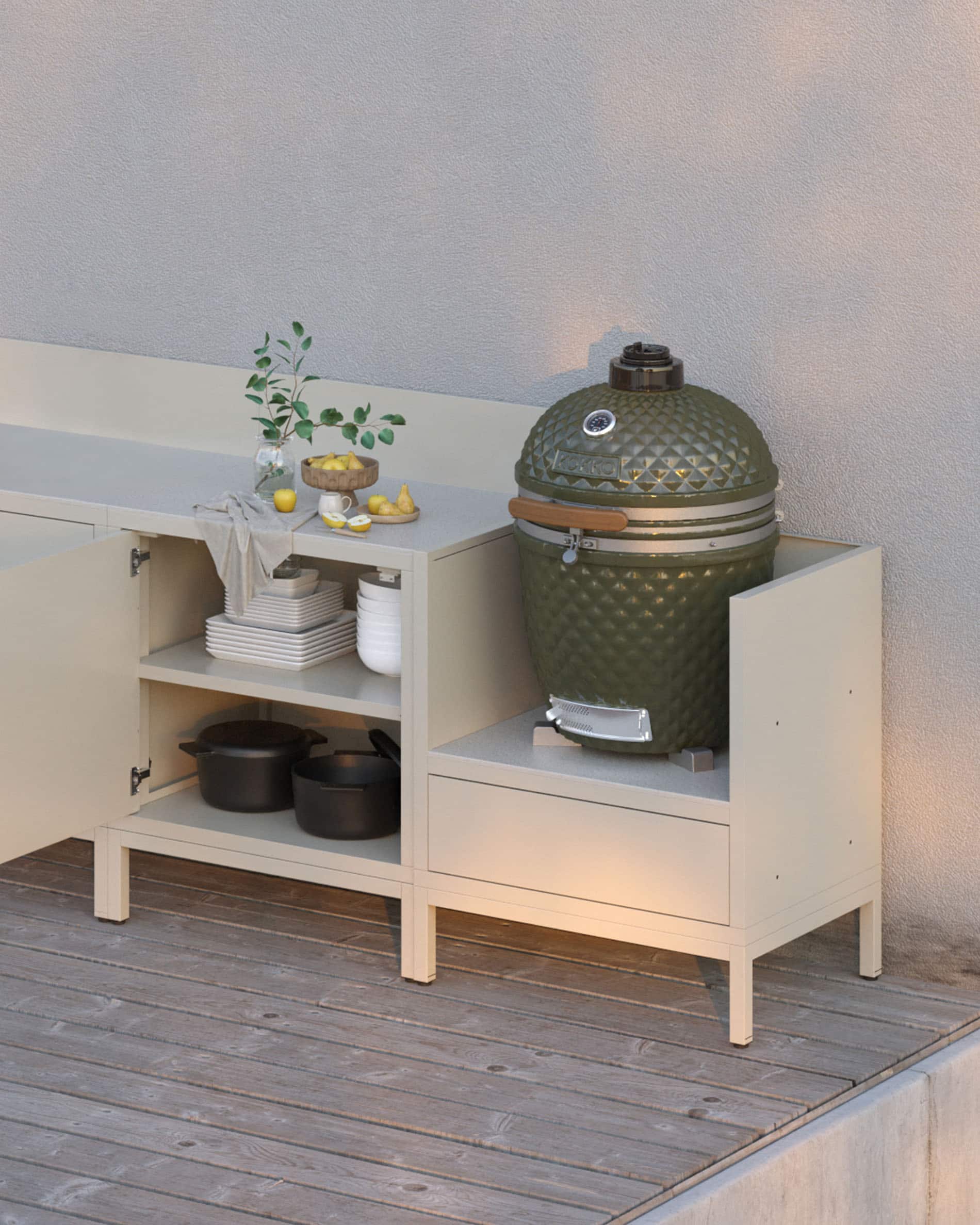 Cucina su palafitte modulare color crema con piano di lavoro chiaro, vani a giorno e modulo dedicato all’integrazione di un kamado.