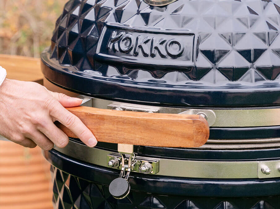 Maniglia frontale in legno di acacia del kamado Kokko nuova edizione, fissata sul coperchio in ceramica nera.