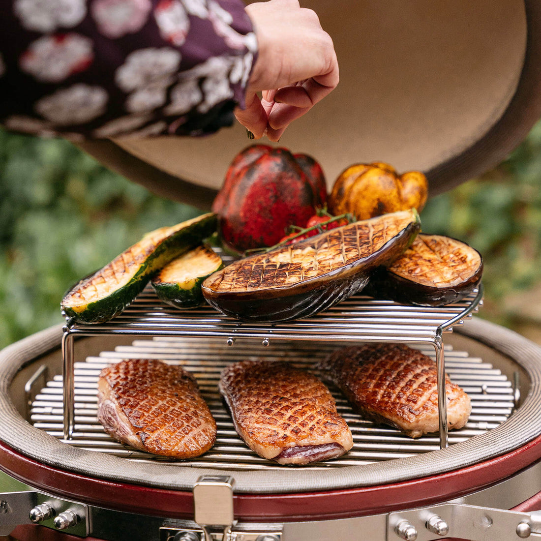 Kamado Kokko 18 pouces en situation de cuisson polyvalente, illustrant la préparation simultanée de différents aliments grâce à la maîtrise de la température et à la cuisson indirecte.
